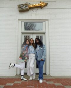 3 members in front of the front door in blue Pi Phi shirts