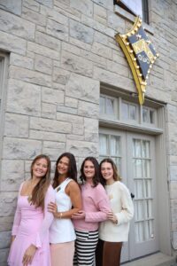 4 sisters outside the house with badge in background