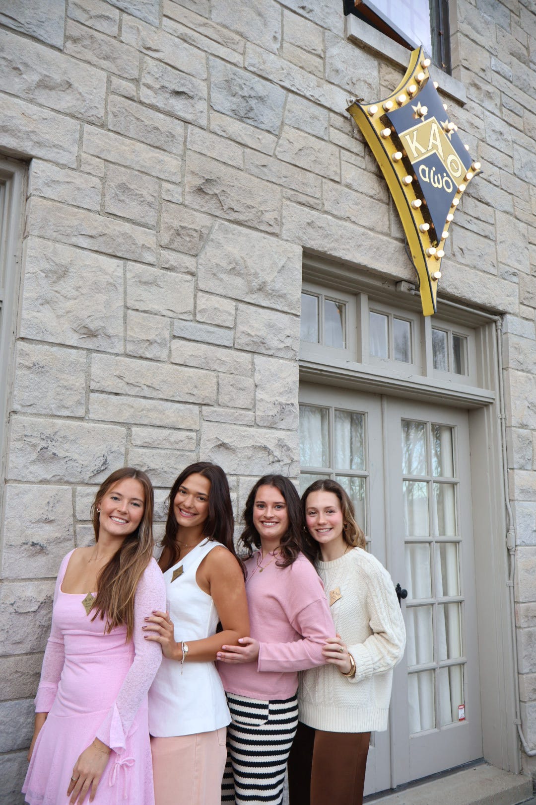 4 sisters outside the house with badge in background