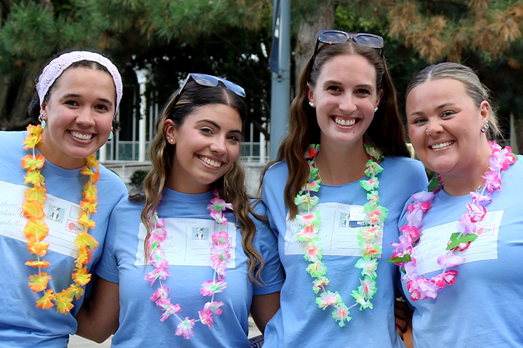 Four women from sororities stand in a group smiling.