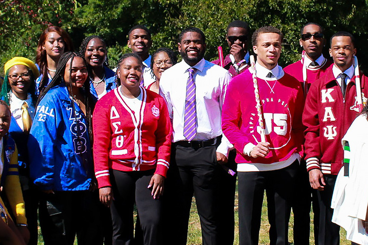 A large group of men and women from Indianapolis NPHC sororities and fraternities stand together smiling.