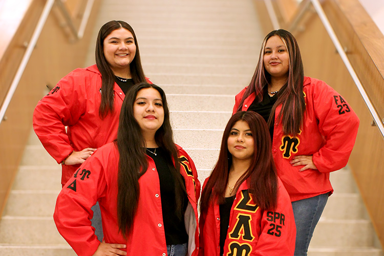 Group of four women from the MCGC pose on stairs wearing red jackets.