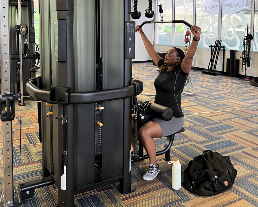 This is a photo of a lady pulling down on a lat bar on a machine in the fitness center.