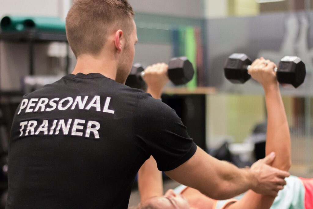 This is a photo of a personal trainer helping a client on the floor in the fitness center.