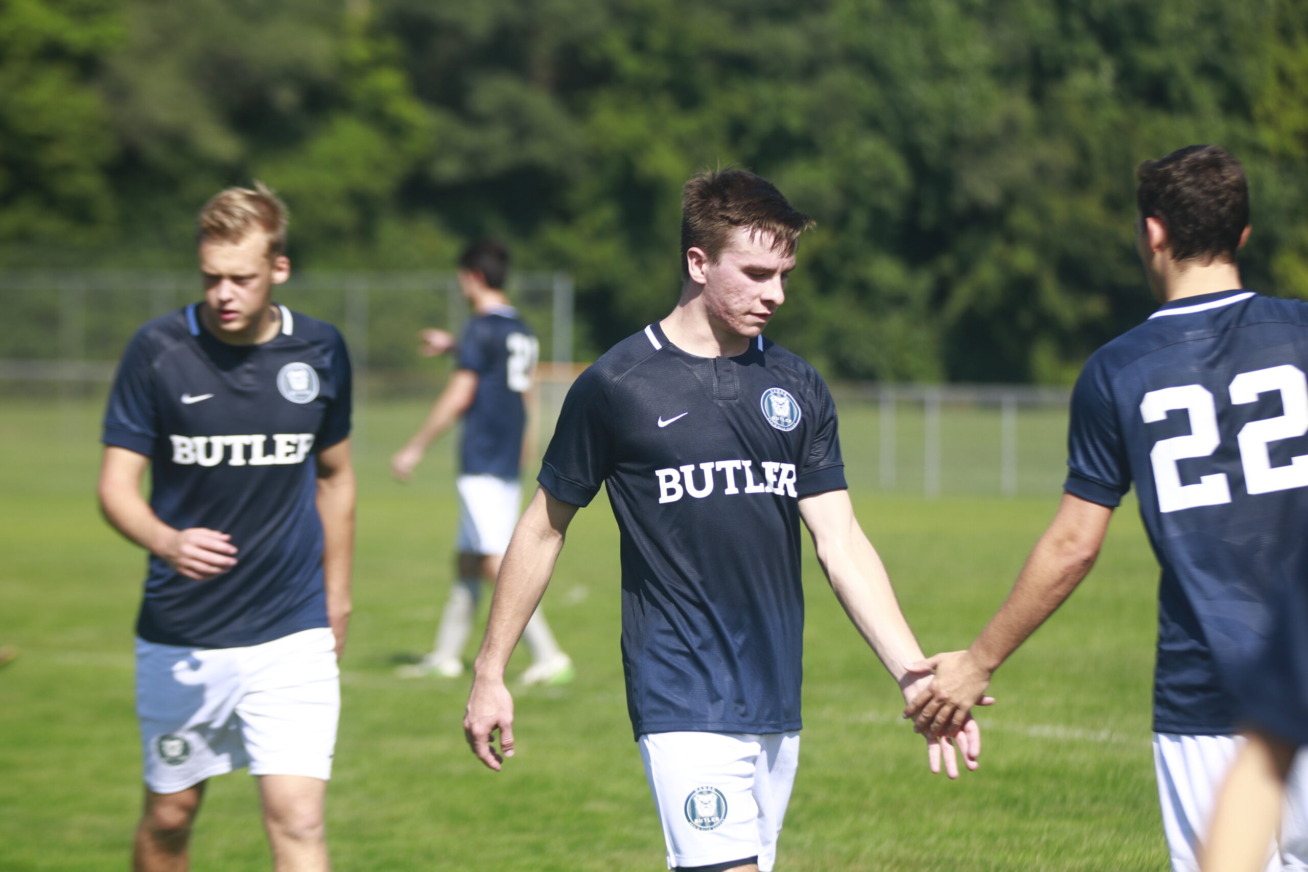 This is a photo of three guys playing soccer on a grass field.