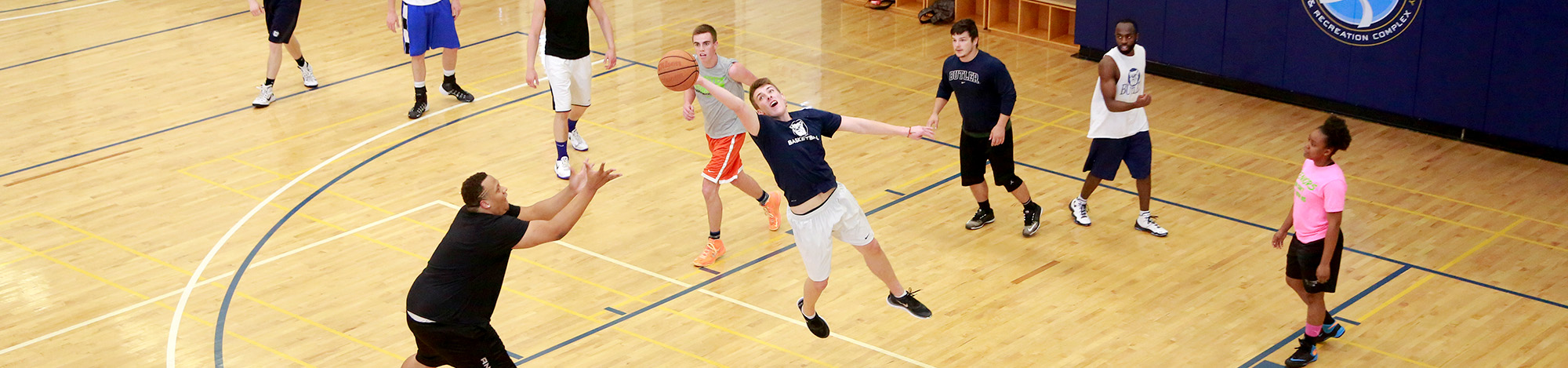 Basketball player stretches to intercept a pass as group of students play a basketball pickup game in the Butler Health and Recreation Complex gymnasium.