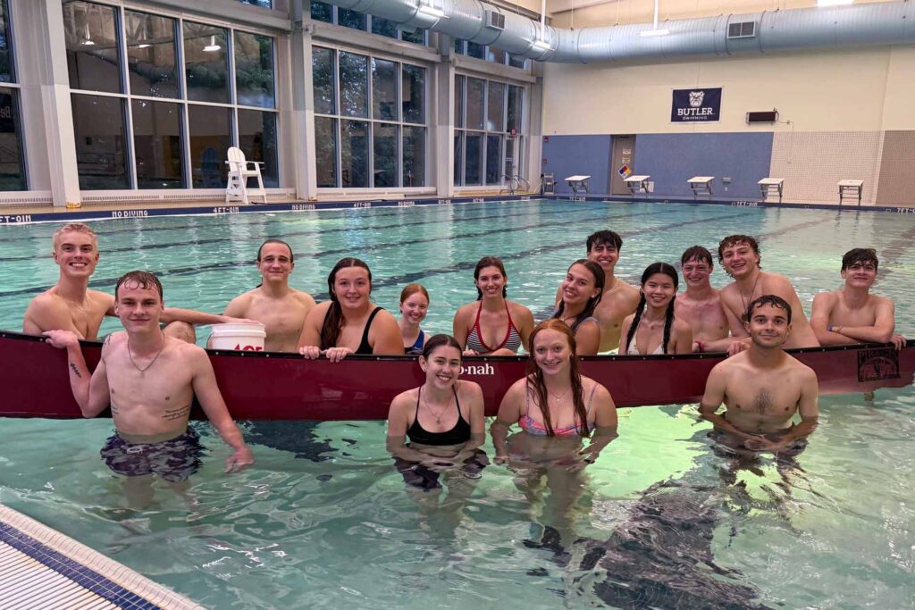 Large group of swimmers smiling in the pool.