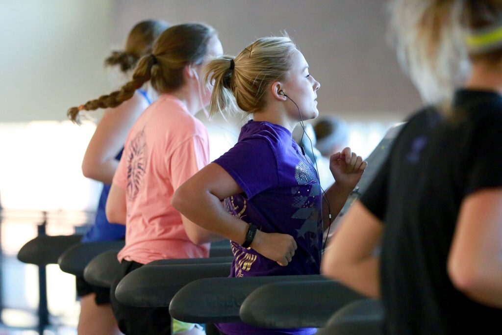 Runners wear headphones while on treadmills.