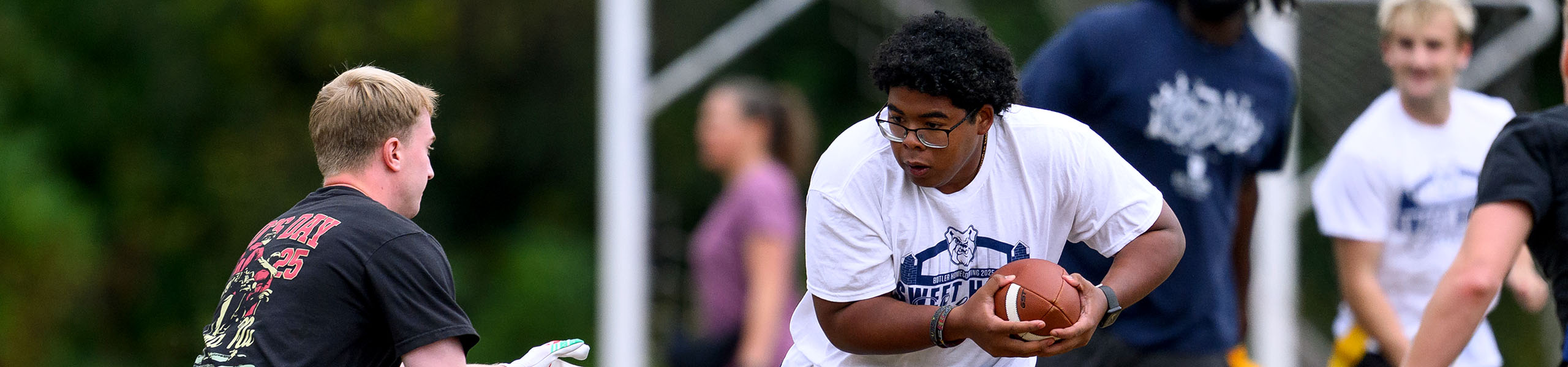 Intramural flag football runner carrying the football evades a tackle.