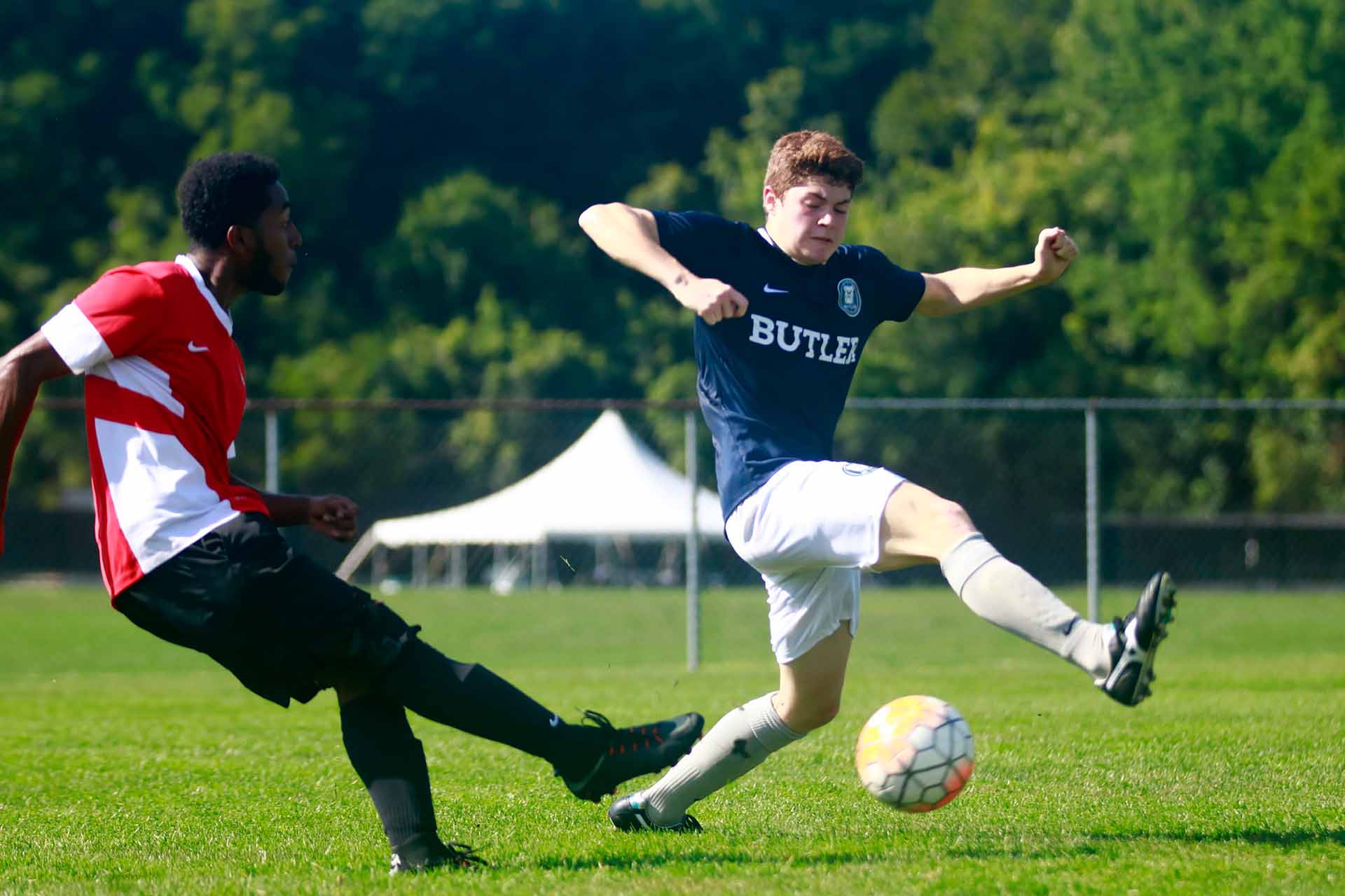 Butler soccer defender sticks out his leg to try to deflect opponent's pass.