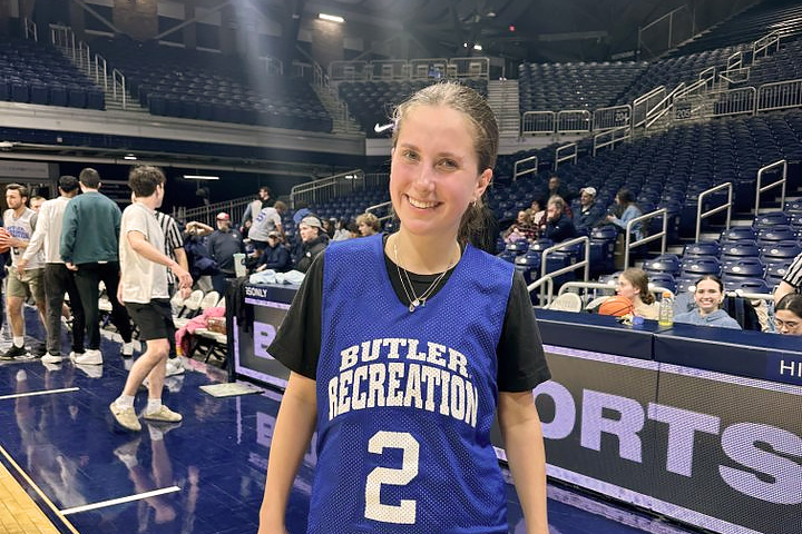 Woman in Butler intramural basketball jersey smiles courtside in Hinkle Fieldhouse.