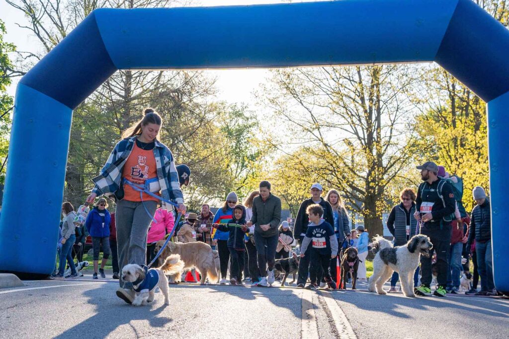 The starting line of the Bulldog Jog event with many people, including children, and dogs on leash.