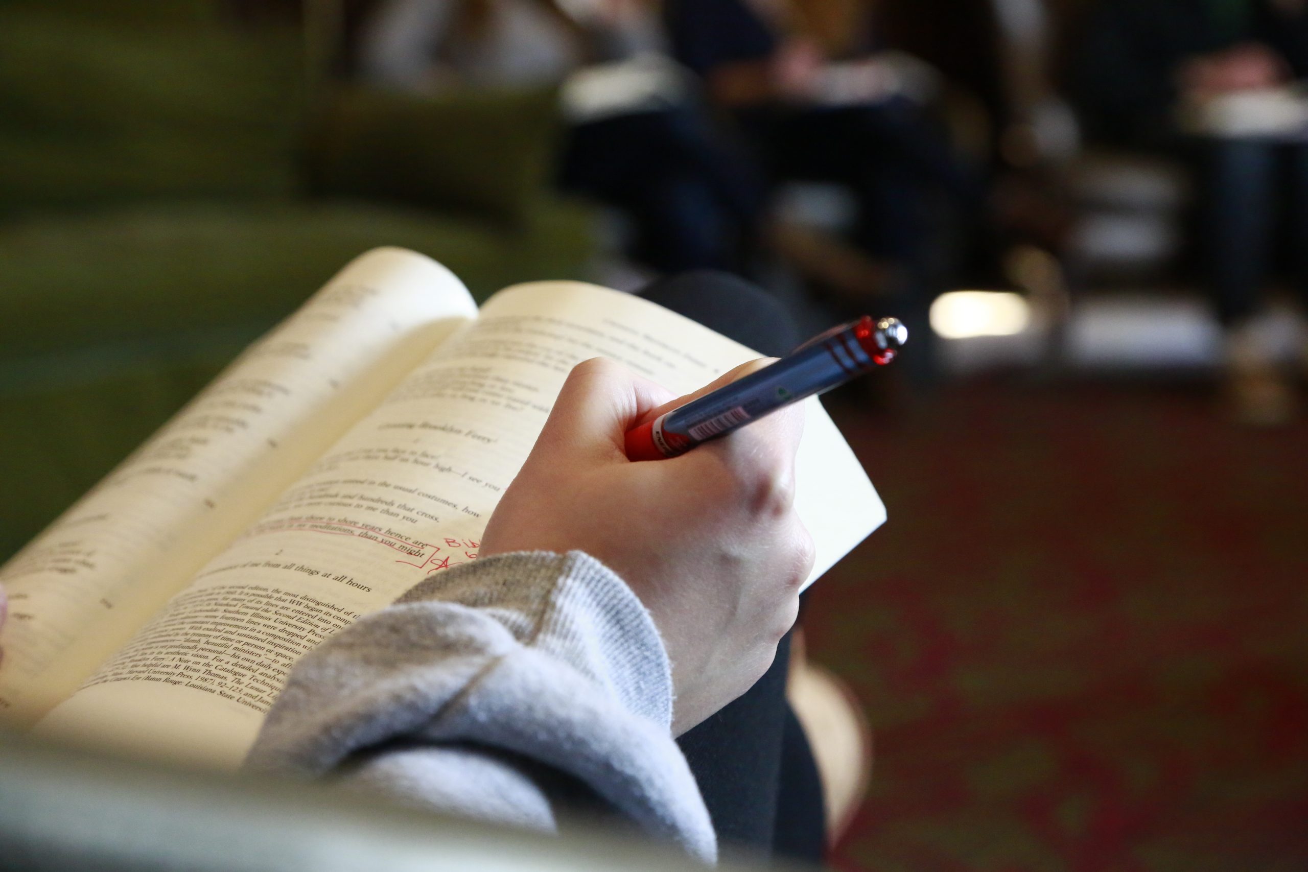 student annotating a book with red pen