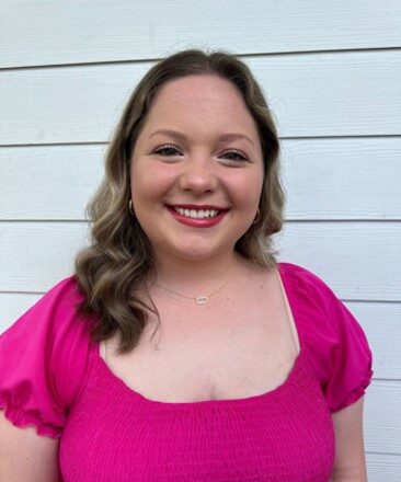 Young woman smiling with long hair and pink shirt