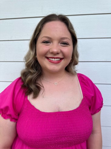 Young woman smiling with long hair and pink shirt