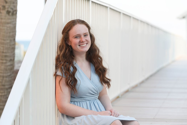 Young woman with long hair smiling and seated on stairs