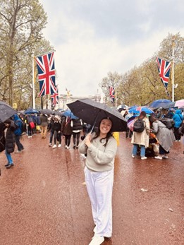 Young woman in white holding an umbrella standing on the sidewalk