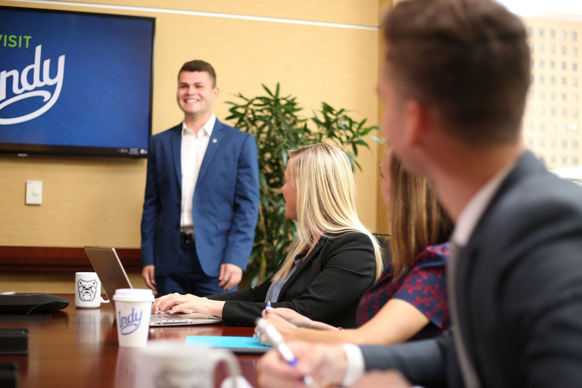 College students in business suits attend meeting in a conference room at the Visit Indy office.