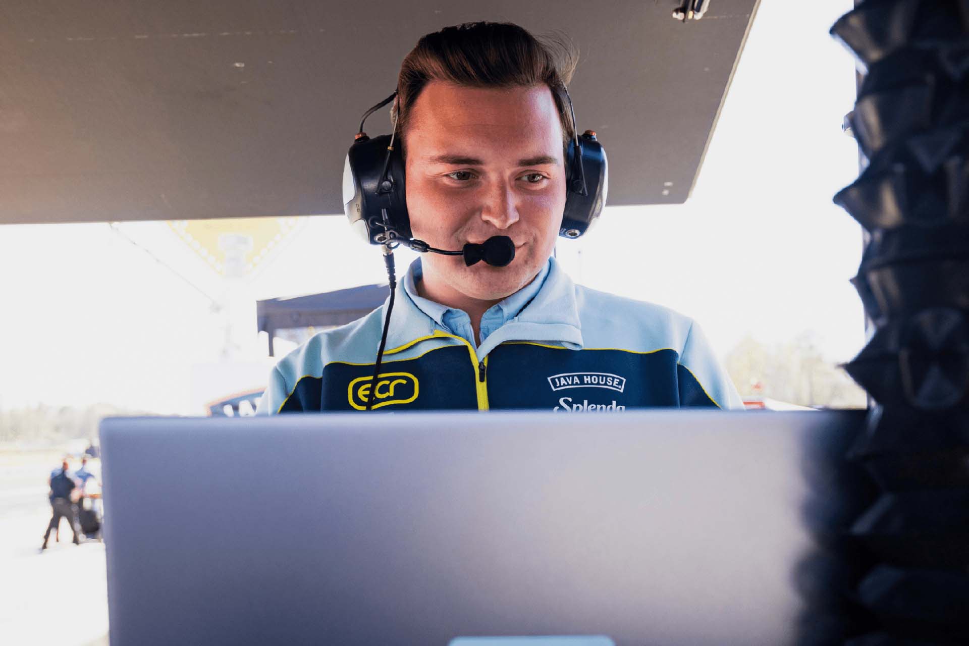 IndyCar engineer Wyatt Harvey wears a headset while working in the tent for his racing team.