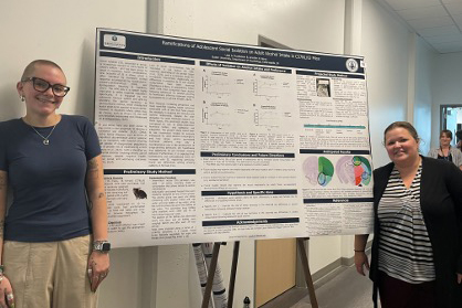 Beckman Scholar Liesl Rozeboom stands with her mentor Dr. Jennifer Berry beside a large poster on an easel.