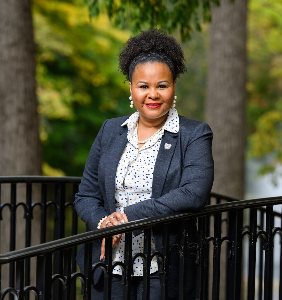 Khalilah Marbury stands by a railing in peaceful garden scene.