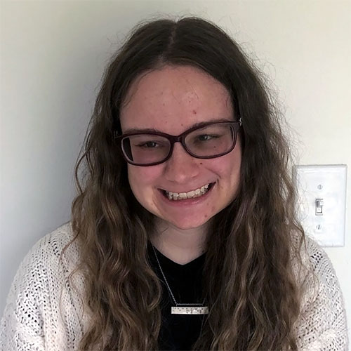 Rachel Apter beams while wearing eyeglasses and a white cardigan