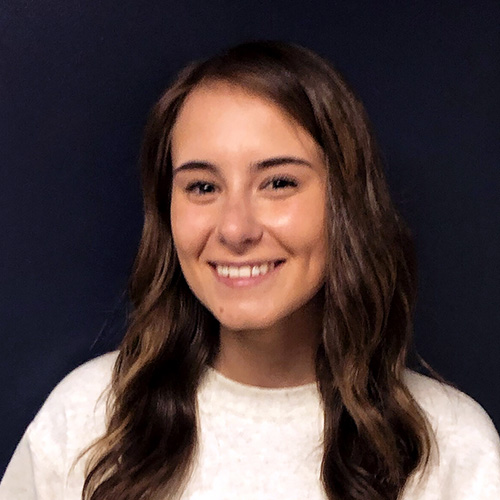 Molly Beier smiles in front of dark blue background.