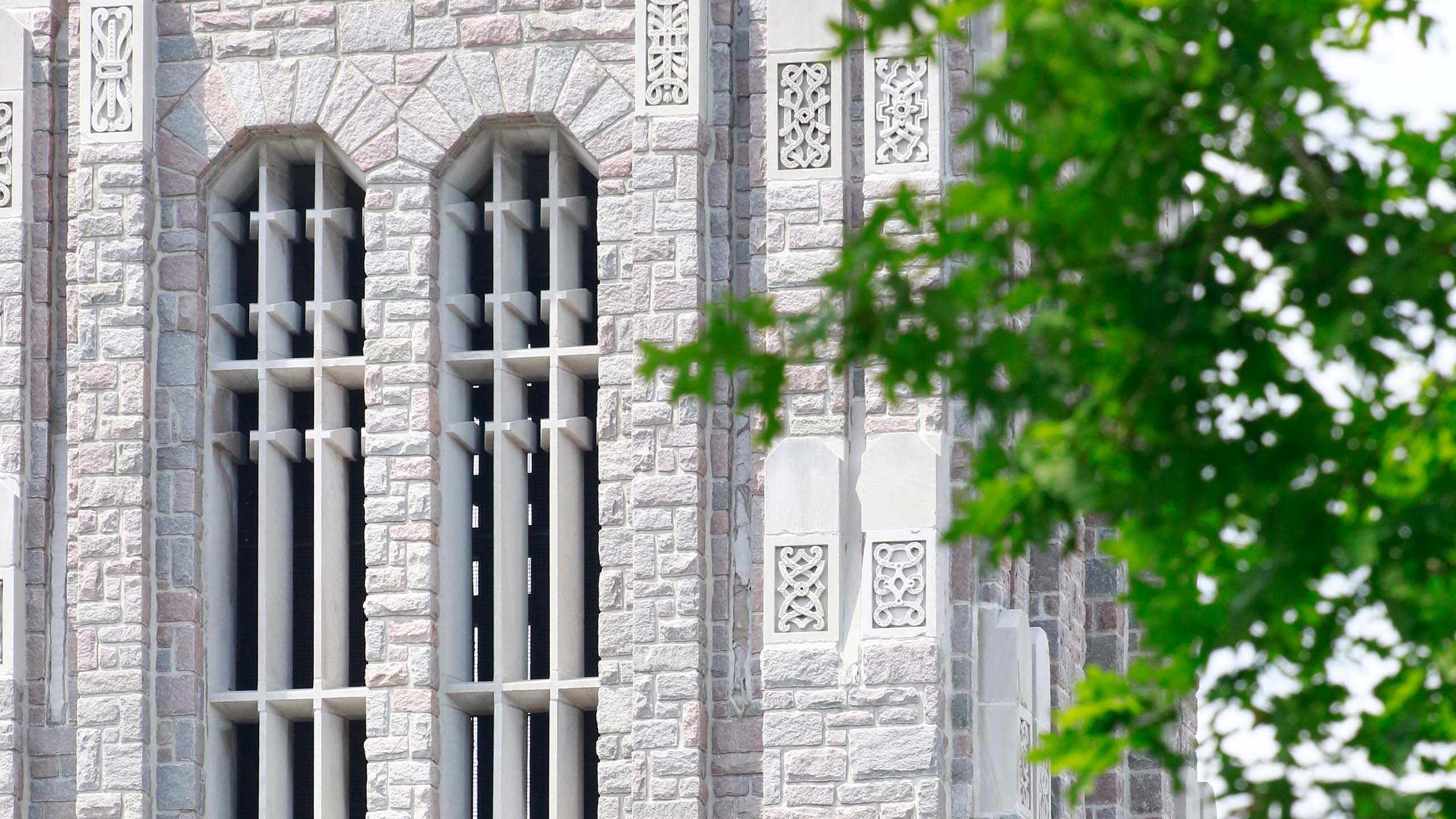 Exterior of limestone Jordan Hall tower with green treetop.