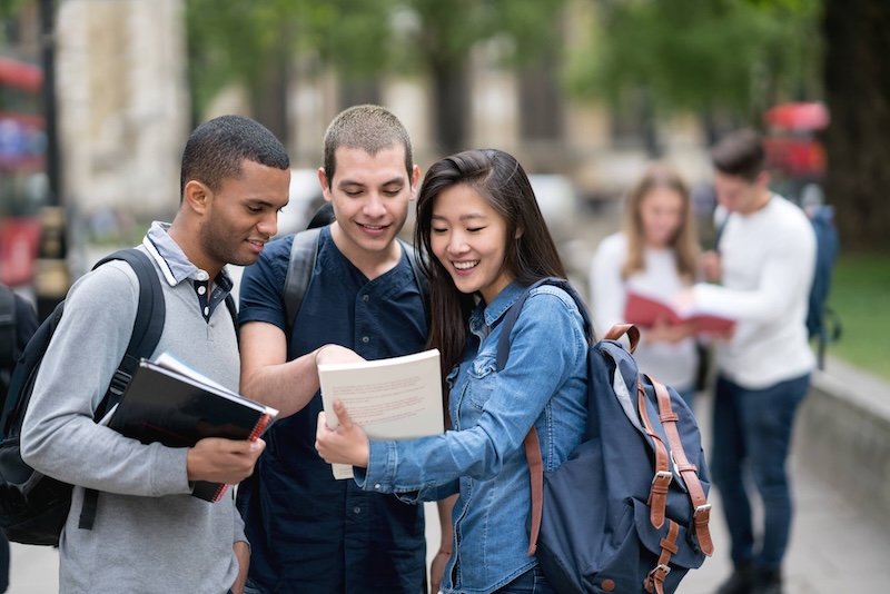 Image of three students together looking at a notebook