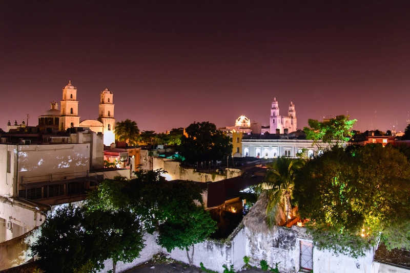 Nighttime view of buildings and trees lit up in Merida, Mexico.