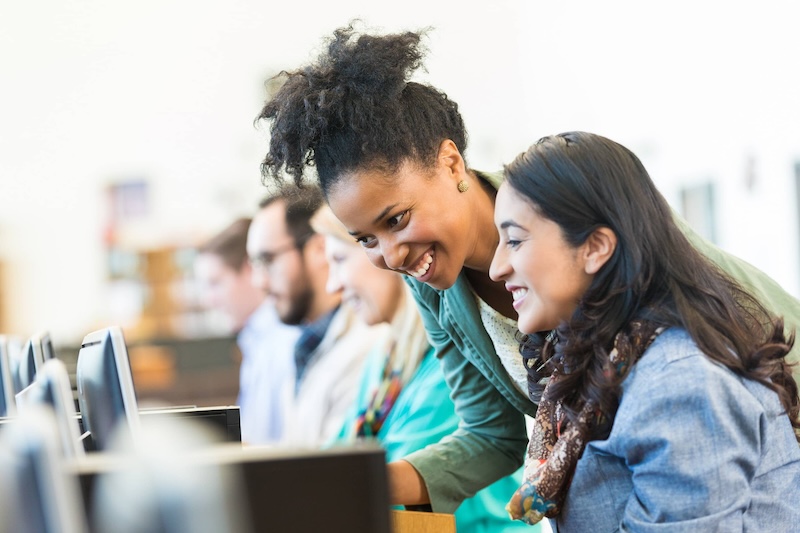 Image of a teacher helping students with computers