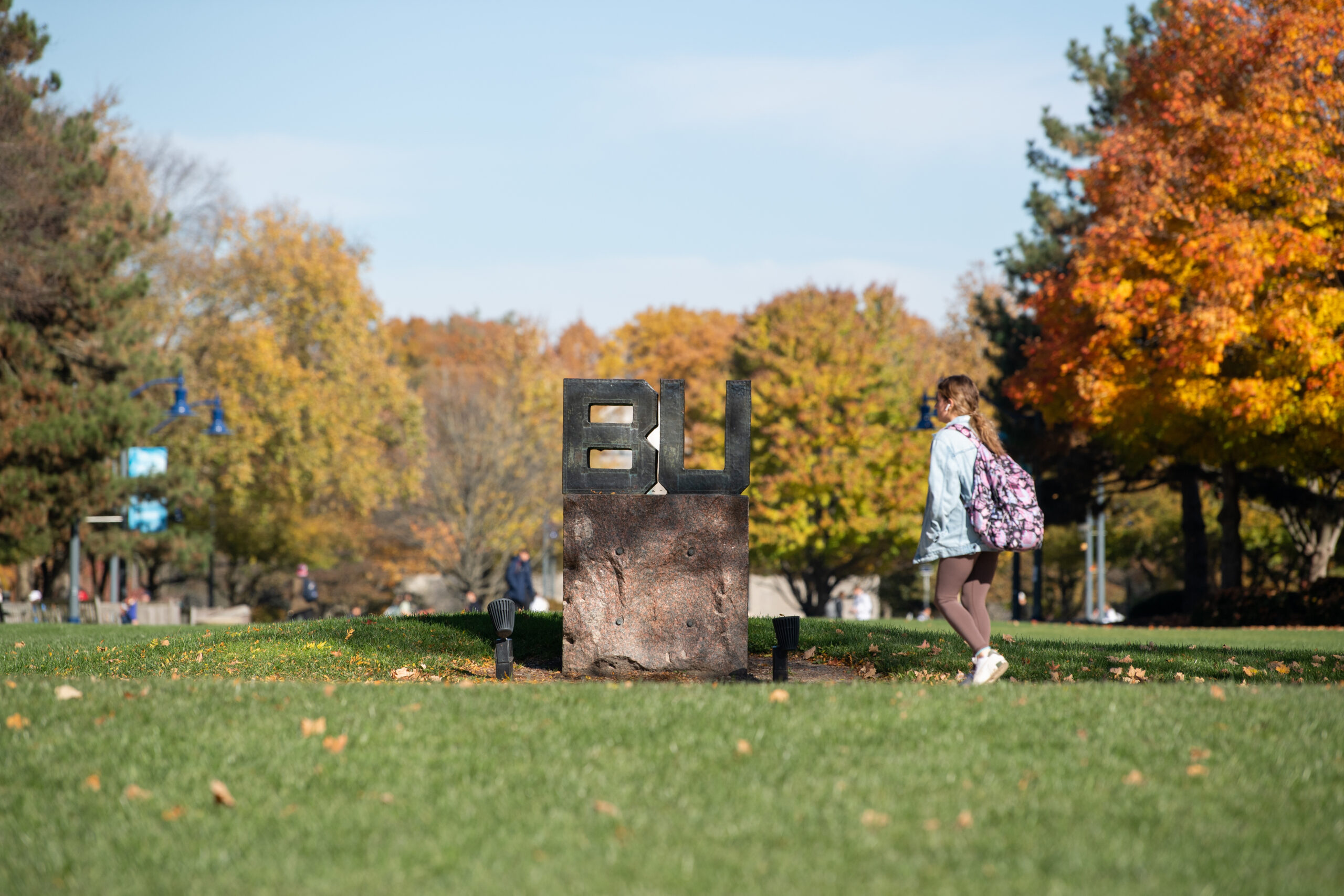 A sign with the letters BU surrounded by fall foliage.
