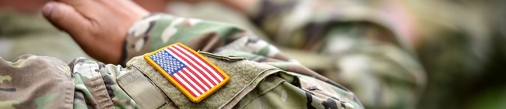 American flag patch on army uniform sleeve of saluting service member
