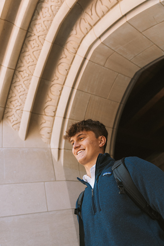 Portrait of Beck Janki smiling as he exits arched stone doorway.