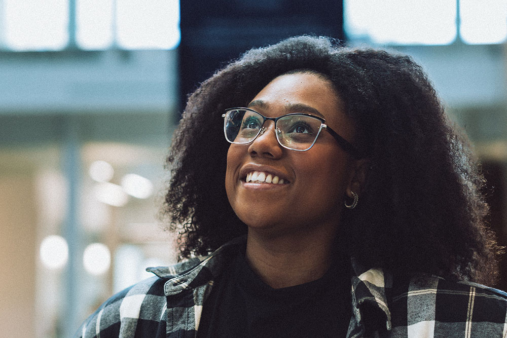 Female student wearing glasses has bright smile as she is gazing upward.