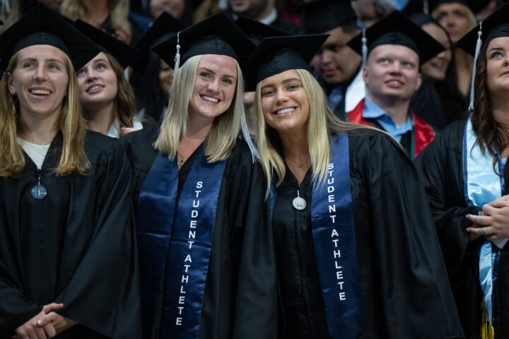 Butler student-athletes smile towards the camera during commencement ceremonies.