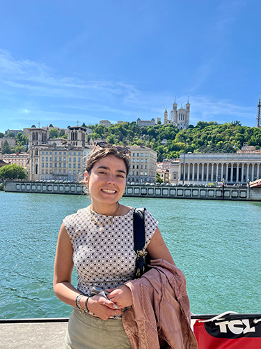 Sarah Miller smiles in front of river and classical architecture in Portugal.